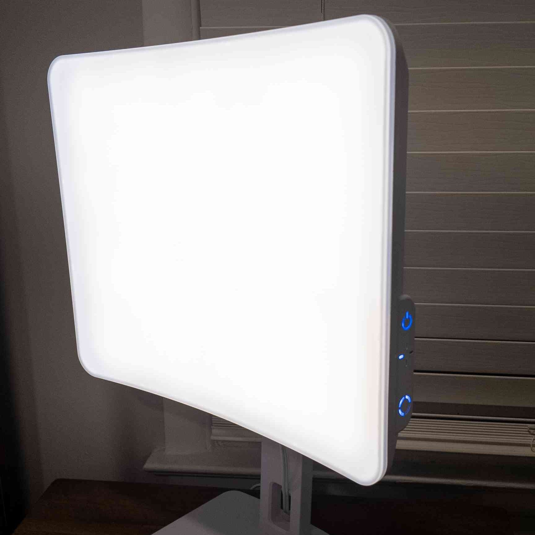 A white light therapy lamp on a table