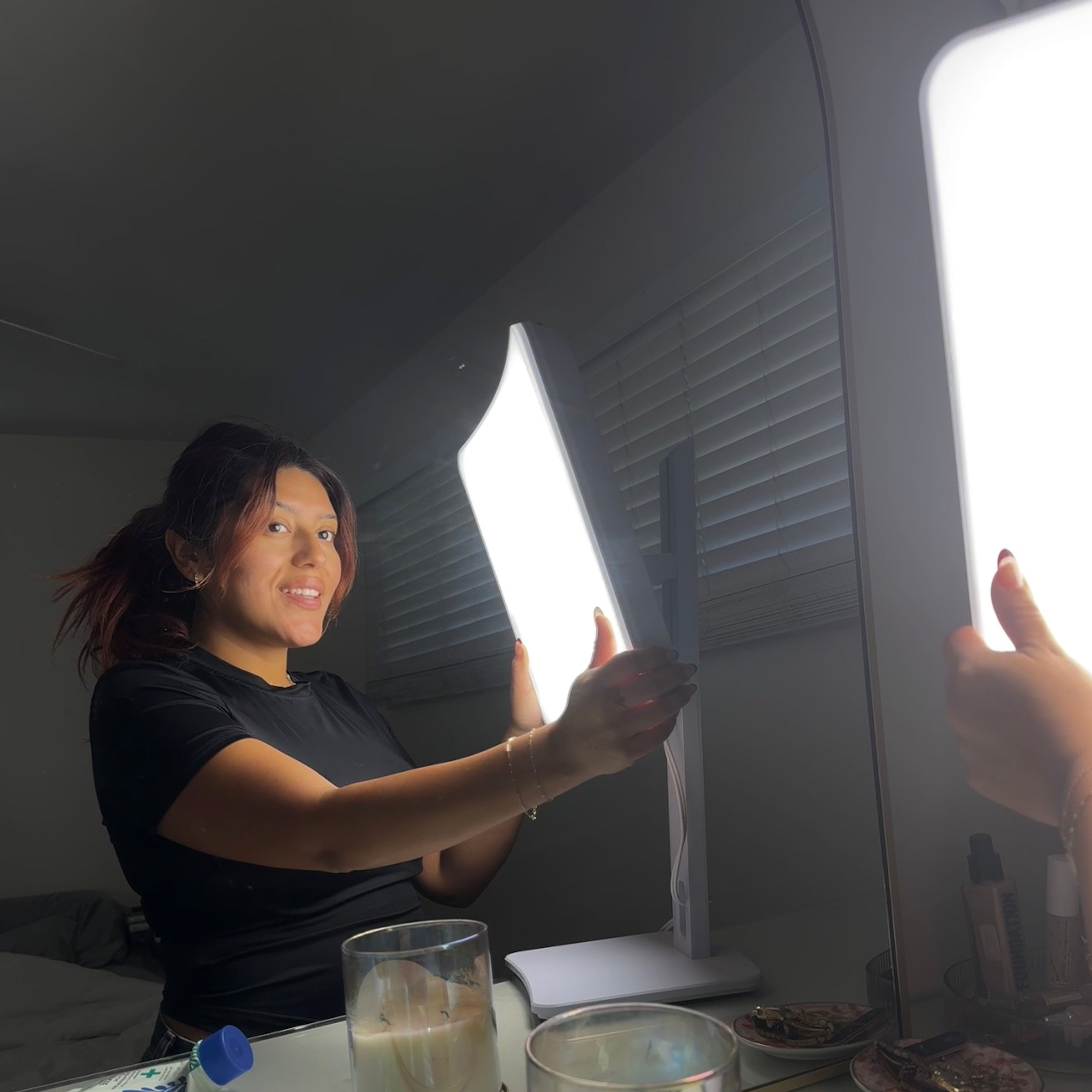 A woman holding a therapy lamp in her bathroom