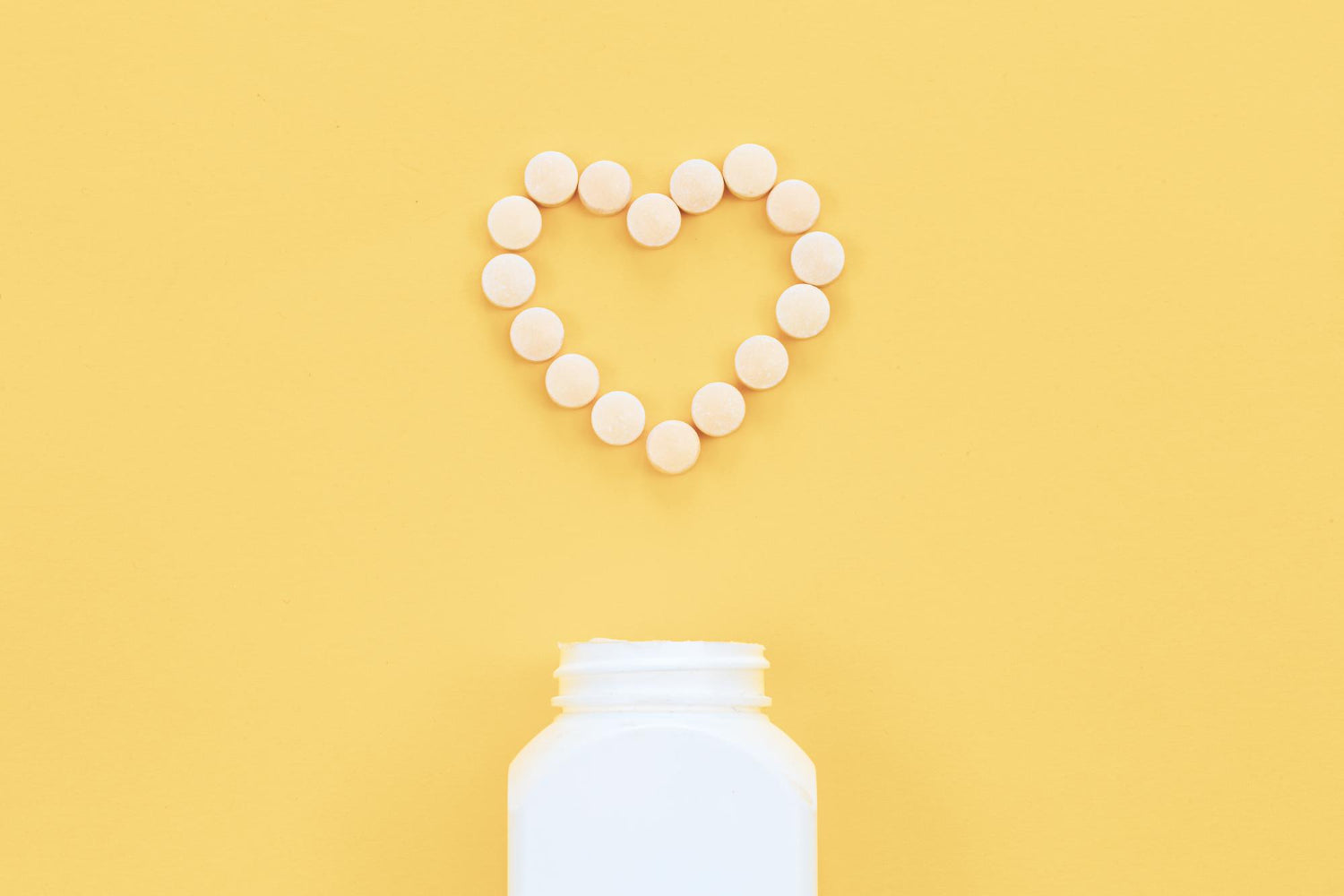 A vitamin bottle with vitamins in a heart shape