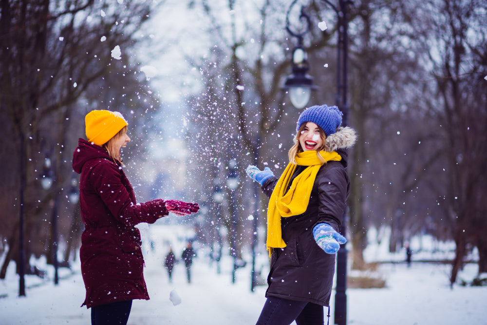 Two women playing in snow, smiling