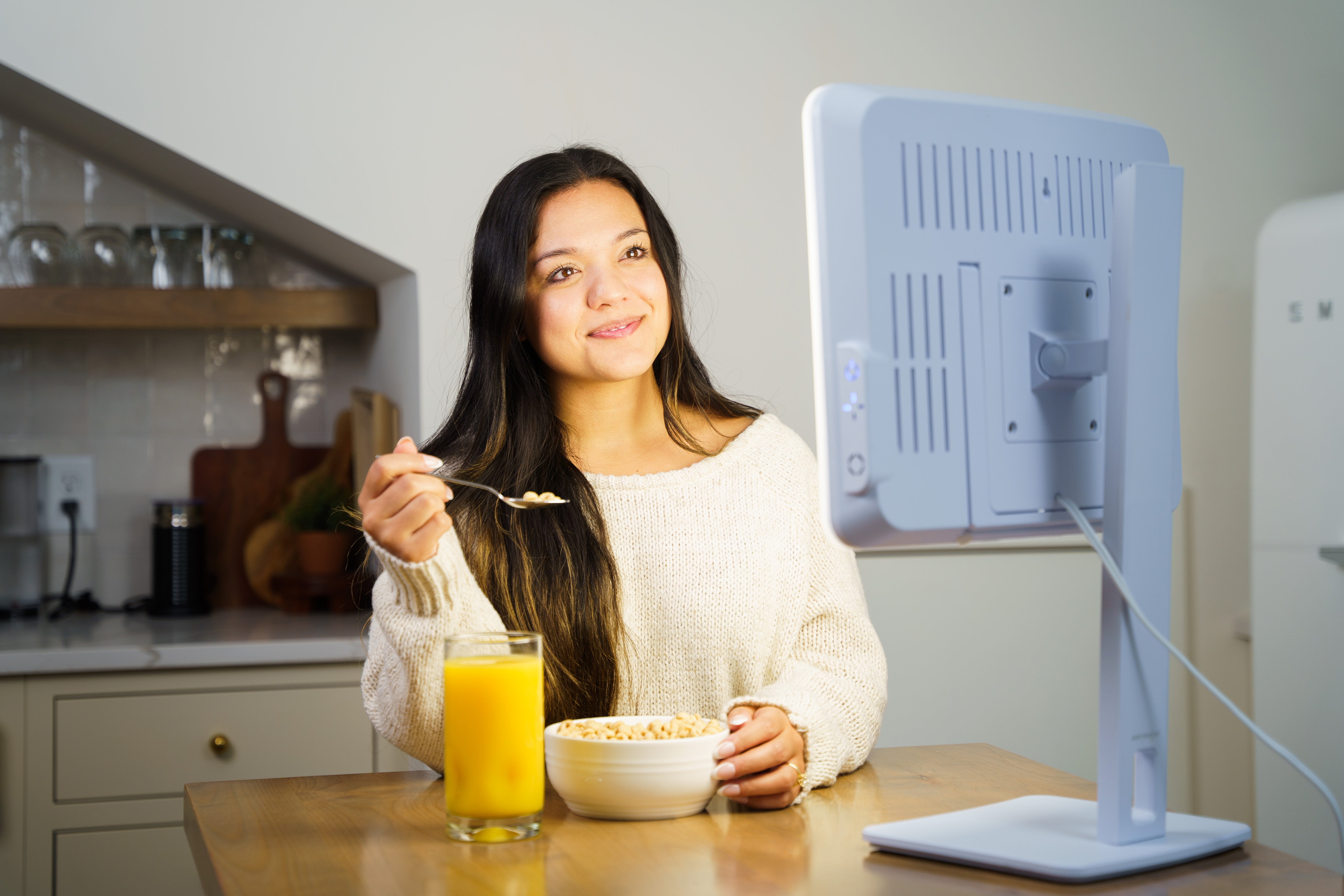 A woman eating cereal in front of a therapy lamp