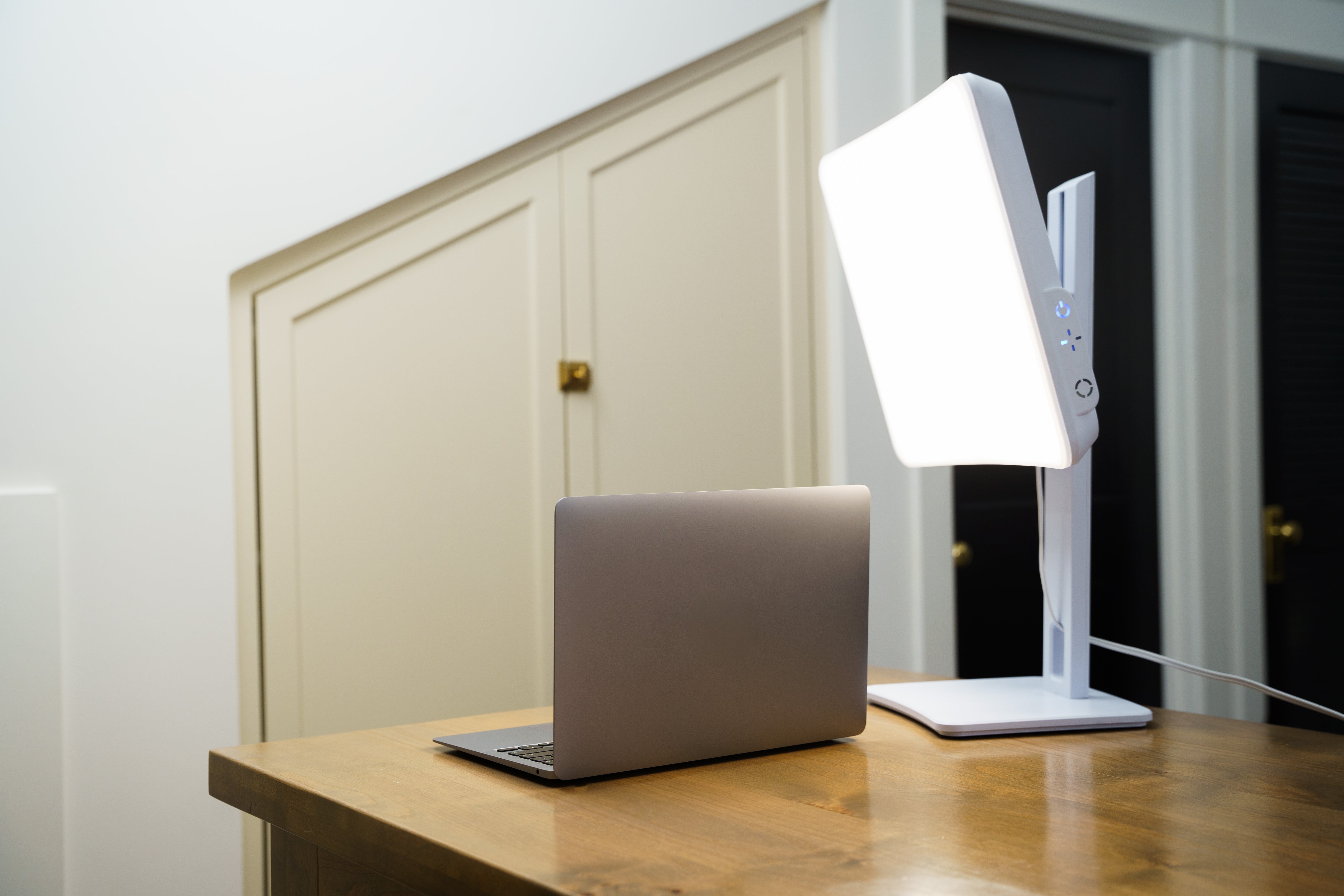 A light therapy lamp on a desk in front of a laptop